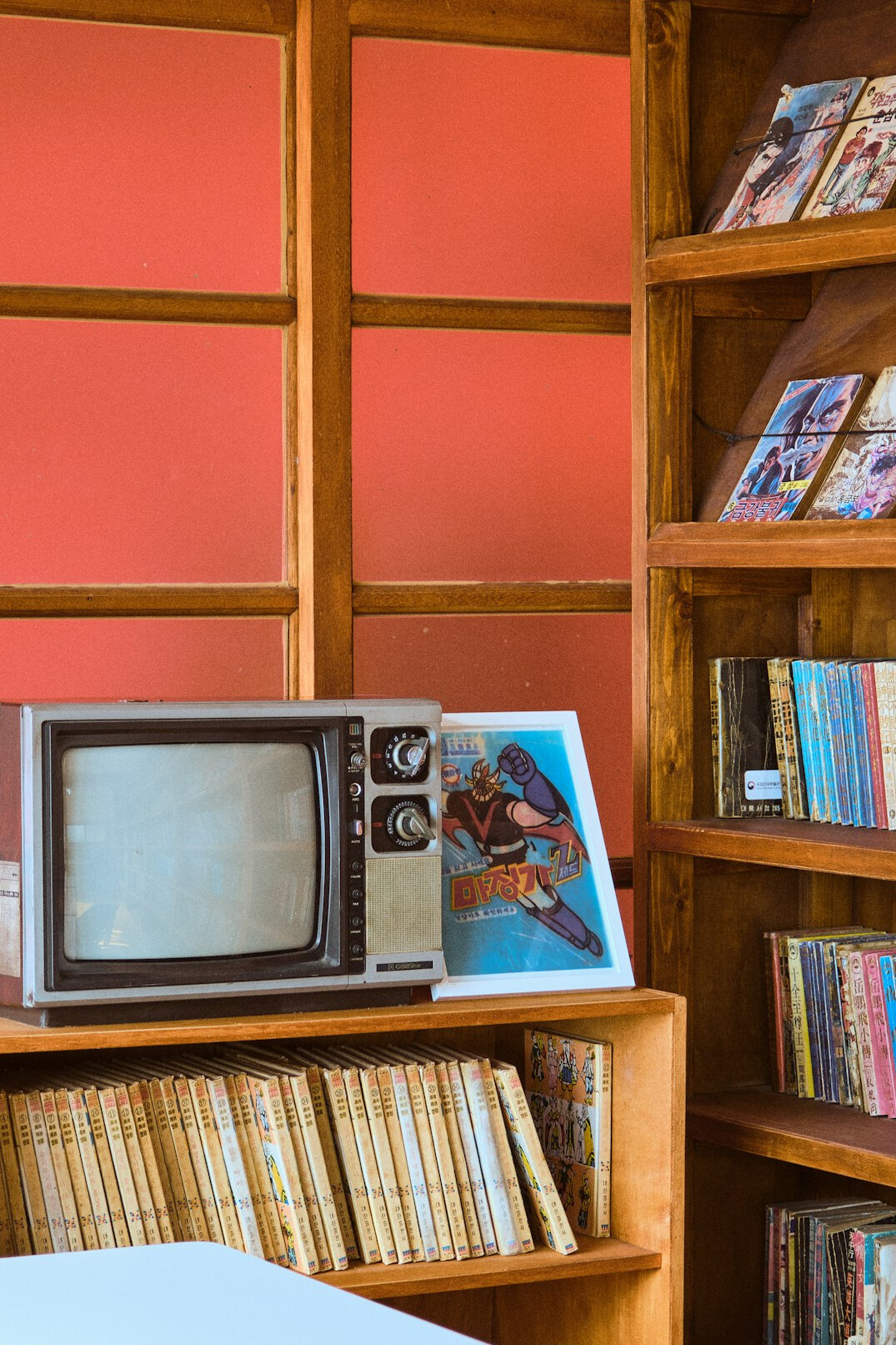 Sala de arquivo de televisão antiga com prateleiras de rolos de película e monitores desligados